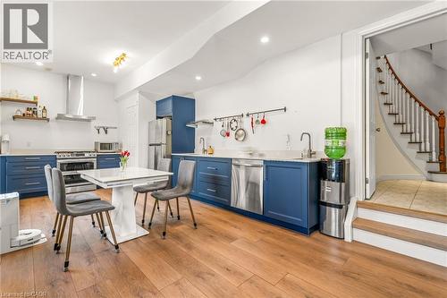 Basement kitchen with blue lower cabinetry, stainless steel appliances, including a gas stove, a range hood, and light marble countertops. - 12 Buman Court, Barrie, ON - Indoor