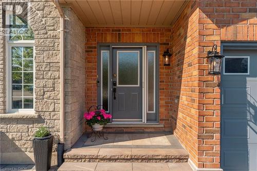 Inviting entryway featuring a dark gray front door with frosted sidelights, exterior brick and stone facade, arched window with grid pattern, and sconce lighting - 12 Buman Court, Barrie, ON - Outdoor With Exterior