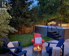 Private backyard oasis featuring a swim spa with integrated steps and handrail, surrounded by lush mature trees and a manicured lawn - 