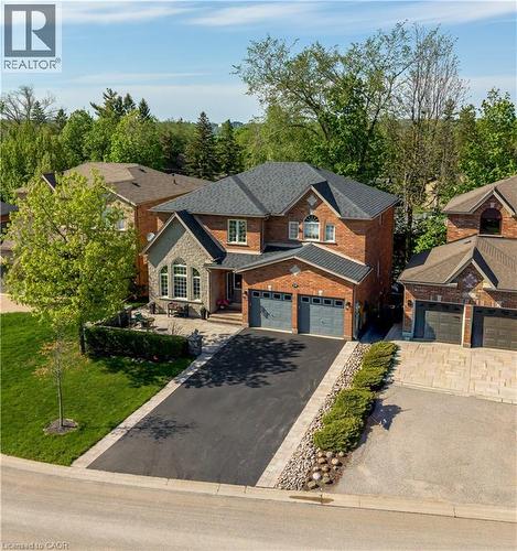 Brick and stone facade residence featuring a two-car garage, dark-toned roof, paved driveway, and manicured landscaping - 12 Buman Court, Barrie, ON - Outdoor With Facade