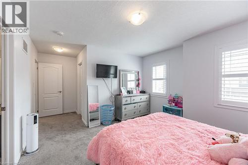 Light-filled interior space featuring two windows with horizontal blinds, neutral wall paint, and gray carpet flooring - 9 Fleming Crescent, Caledonia, ON - Indoor Photo Showing Bedroom