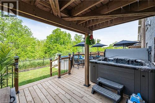 Spacious outdoor deck featuring a hot tub, a covered seating area, and a green space beyond the perimeter fencing - 9 Fleming Crescent, Caledonia, ON - Outdoor With Deck Patio Veranda With Exterior
