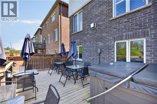 Expansive wood deck with a built-in hot tub, dark brick exterior, and multiple windows - 9 Fleming Crescent, Caledonia, ON - Outdoor With Deck Patio Veranda With Exterior