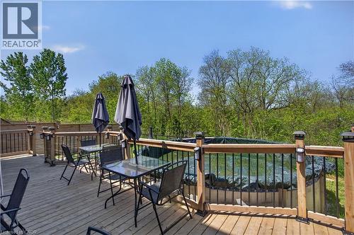 Expansive wooden deck with a built-in above-ground pool, surrounded by a wooden privacy fence and mature trees - 9 Fleming Crescent, Caledonia, ON - Outdoor With Deck Patio Veranda