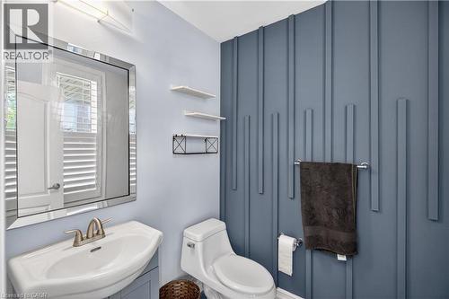 Contemporary powder room featuring a decorative accent wall with vertical paneling, a wall-mounted sink with brushed nickel faucet, a frameless beveled mirror, and recessed lighting - 9 Fleming Crescent, Caledonia, ON - Indoor Photo Showing Bathroom