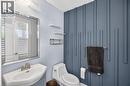 Contemporary powder room featuring a decorative accent wall with vertical paneling, a wall-mounted sink with brushed nickel faucet, a frameless beveled mirror, and recessed lighting - 9 Fleming Crescent, Caledonia, ON  - Indoor Photo Showing Bathroom 