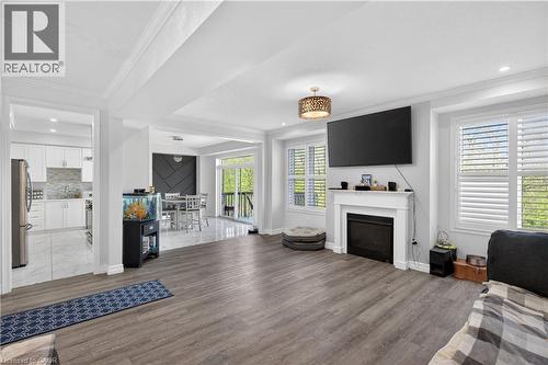 Spacious living area featuring wood-finish flooring, a white mantel fireplace, and multiple windows with plantation shutters - 9 Fleming Crescent, Caledonia, ON - Indoor With Fireplace