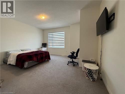 Carpeted interior space featuring a window with horizontal blinds, a wall-mounted television, and a flush-mount ceiling light fixture - 18 Dolucci Crescent, Brampton, ON - Indoor Photo Showing Bedroom