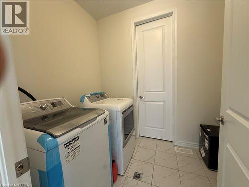 Laundry area featuring light-toned walls, a white paneled door with a silver knob, and light-toned square floor tiles - 18 Dolucci Crescent, Brampton, ON - Indoor Photo Showing Laundry Room