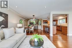 Open-concept living area featuring rich wood-finish flooring, recessed lighting, and a kitchen with wood cabinetry, granite countertops, and stainless steel appliances - 