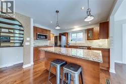 Kitchen featuring wood-finish flooring, recessed lighting, and a center island with a stone countertop - 