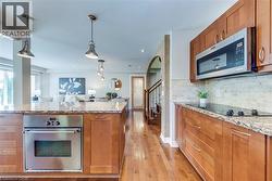 Kitchen featuring wood cabinetry, stainless steel appliances, and stone countertops - 