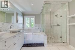 Contemporary bathroom featuring a glass-enclosed shower with pebble-tile flooring, a separate soaking tub, and a dual-sink vanity with vessel sinks - 
