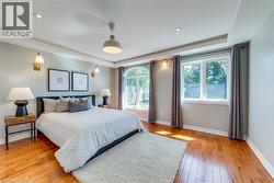 Spacious room featuring wood-finish flooring, multiple windows, and a tray ceiling - 