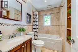 Full bathroom featuring a single vanity with wood-finish cabinetry, a drop-in sink, and a chrome faucet - 