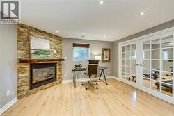 Recessed lighting highlights the stone-clad gas fireplace with a wood-finish mantel - 