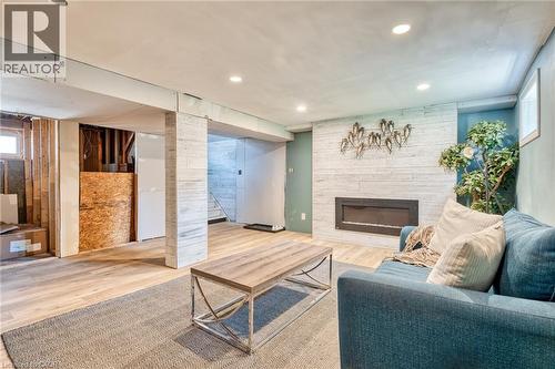 Contemporary living space featuring a modern fireplace with a white shiplap-style surround, recessed lighting, and wood-finish flooring - 151 Winchester Boulevard, Hamilton, ON - Indoor With Fireplace