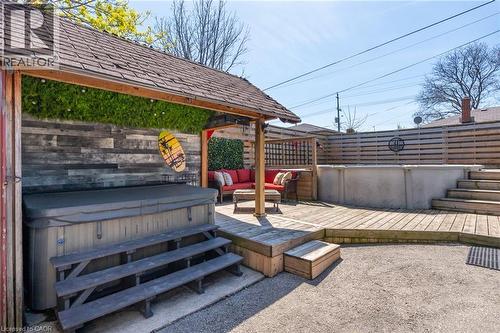 Outdoor living space featuring a built-in hot tub with tiered steps, a raised wooden deck, and an above-ground pool - 151 Winchester Boulevard, Hamilton, ON - Outdoor