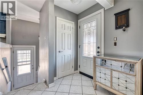 Entryway featuring white square floor tiles, a decorative front door with leaded glass, and an additional white paneled interior door - 151 Winchester Boulevard, Hamilton, ON - Indoor Photo Showing Other Room