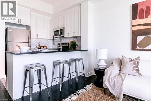 Kitchenette featuring white cabinetry, stainless steel appliances, dark countertops, and a white herringbone tile backsplash - 101 Shoreview Place Unit# 631, Stoney Creek, ON - Indoor Photo Showing Other Room