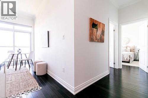 Dark wood-finish flooring throughout, white baseboards, and bright white walls - 101 Shoreview Place Unit# 631, Stoney Creek, ON - Indoor Photo Showing Other Room