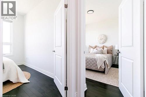 Interior doors with paneled detailing open to rooms featuring dark wood-finish flooring, white baseboards, and bright white walls - 101 Shoreview Place Unit# 631, Stoney Creek, ON - Indoor Photo Showing Bedroom