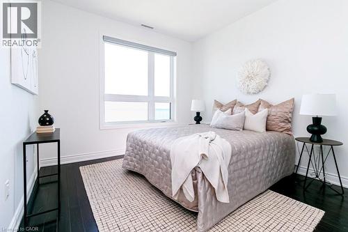 Bright room featuring a large picture window, dark wood-finish flooring, white baseboards, and white walls - 101 Shoreview Place Unit# 631, Stoney Creek, ON - Indoor Photo Showing Bedroom