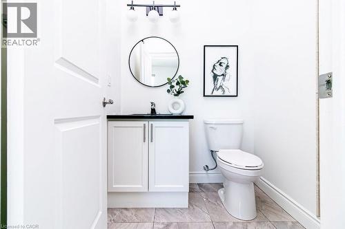 White vanity with black countertop and chrome faucet, under a circular mirror with black frame - 101 Shoreview Place Unit# 631, Stoney Creek, ON - Indoor Photo Showing Bathroom