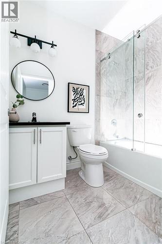 Contemporary bathroom featuring a white vanity with black countertop, a round mirror, and a three-light matte black fixture - 101 Shoreview Place Unit# 631, Stoney Creek, ON - Indoor Photo Showing Bathroom