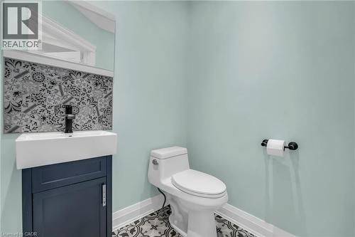 Modern powder room featuring a wall-mounted rectangular mirror, decorative tile backsplash, and a contemporary vanity with a vessel sink and matte black faucet - 25 Park Street E, Hamilton, ON - Indoor Photo Showing Bathroom