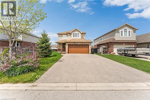 Two-story residence featuring brick and siding facade, an attached garage with a wood-finish door, a paved driveway, and landscaped front yard with mature trees and flowering shrubs - 139 Ferris Drive, Wellesley, ON - Outdoor