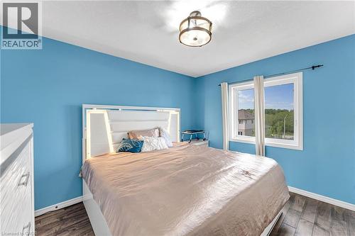 Bright room featuring wood-finish flooring, a contemporary ceiling light fixture, and a large window with white trim - 139 Ferris Drive, Wellesley, ON - Indoor Photo Showing Bedroom