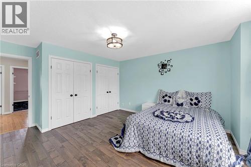 Spacious room featuring wood-finish flooring, two sets of bi-fold closet doors, light blue walls, and a contemporary ceiling light fixture - 139 Ferris Drive, Wellesley, ON - Indoor Photo Showing Bedroom