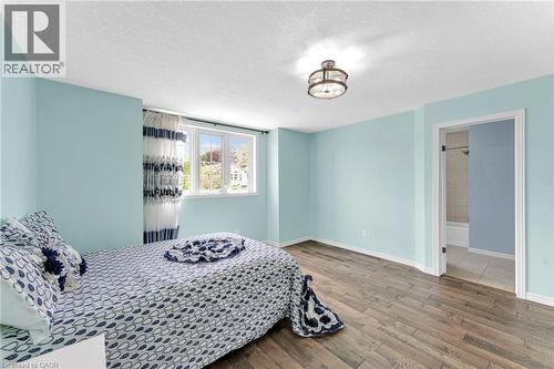 Spacious bedroom featuring wood-finish flooring, light blue walls, and a large window - 139 Ferris Drive, Wellesley, ON - Indoor Photo Showing Bedroom
