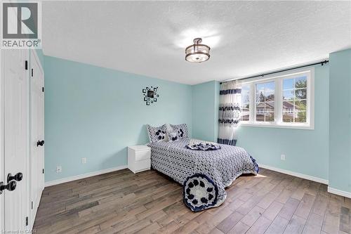 Bright room featuring wood-finish flooring, a large window with white framing, and a ceiling-mounted light fixture - 139 Ferris Drive, Wellesley, ON - Indoor Photo Showing Bedroom
