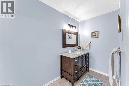 Bathroom featuring a dark wood-finish vanity with a light-colored countertop, an undermount sink, and a framed mirror - 139 Ferris Drive, Wellesley, ON - Indoor