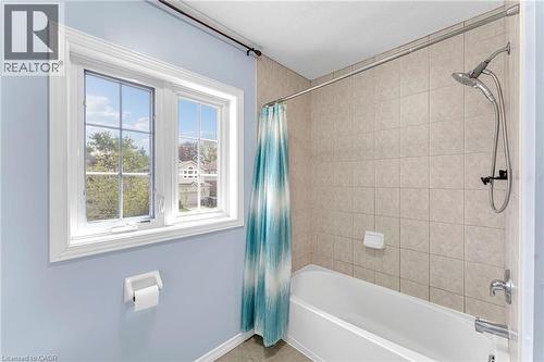 Bathroom featuring a white framed window with gridded panes, light blue painted walls, a white bathtub, and light-toned square wall tiles - 139 Ferris Drive, Wellesley, ON - Indoor Photo Showing Bathroom
