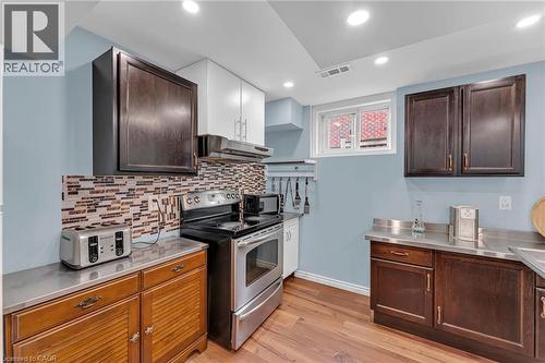 Kitchen featuring wood-finish flooring, a stainless steel range, and a mosaic tile backsplash - 139 Ferris Drive, Wellesley, ON - Indoor Photo Showing Kitchen