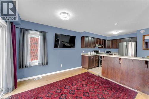 Open-concept living space featuring wood-finish flooring, a kitchen island with seating, dark wood cabinetry, and stainless steel appliances - 139 Ferris Drive, Wellesley, ON - Indoor Photo Showing Kitchen