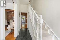 Foyer featuring white painted staircase with carpet runner, dark tiled flooring, and exposed brick wall accents - 