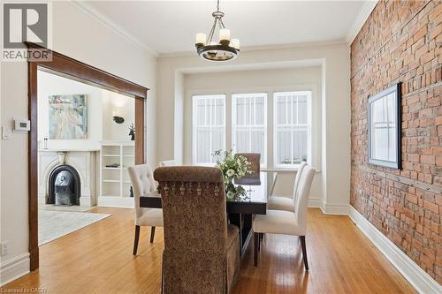 Hardwood flooring throughout the dining area and adjacent room, featuring a classic exposed brick wall - 314 Hess Street S, Hamilton, ON - Indoor Photo Showing Dining Room
