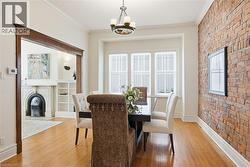 Hardwood flooring throughout the dining area and adjacent room, featuring a classic exposed brick wall - 