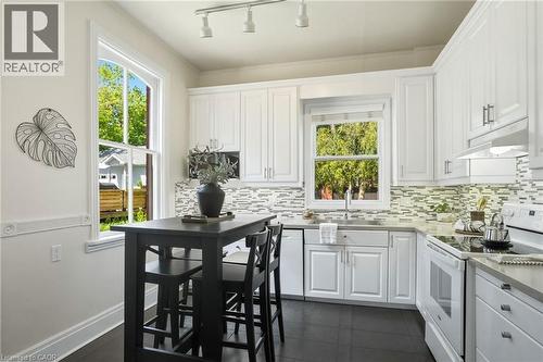 Kitchen featuring white shaker-style cabinetry, a mosaic tile backsplash, stainless steel sink, and gray countertops - 314 Hess Street S, Hamilton, ON - Indoor