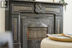 Ornate cast iron fireplace with intricate scrollwork, a decorative grate, shield motif, and contrasting textured panels - 