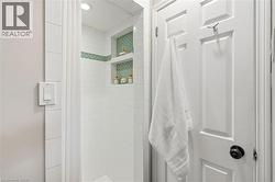 Shower featuring white subway tile surround, recessed lighting, and two built-in tile niches with green mosaic accents - 