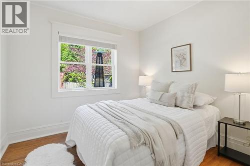 Light-filled room featuring hardwood flooring, white trim, and a prominent window - 314 Hess Street S, Hamilton, ON - Indoor Photo Showing Bedroom