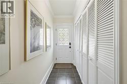 Entryway with dark tile flooring, white crown molding, and white louvered bifold closet doors - 