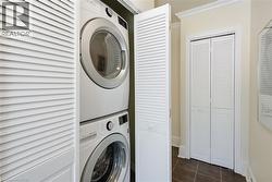 Stacked washer and dryer unit concealed behind louvered bifold doors - 