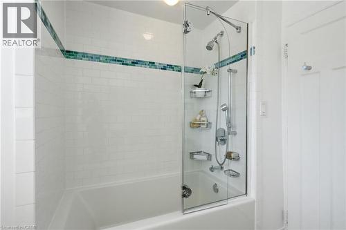 Bathtub and shower combination featuring white subway tile surround, a decorative tile accent band, and a clear glass shower panel - 314 Hess Street S, Hamilton, ON - Indoor Photo Showing Bathroom