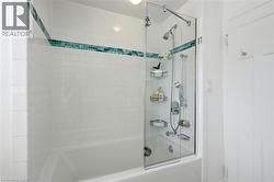 Bathtub and shower combination featuring white subway tile surround, a decorative tile accent band, and a clear glass shower panel - 